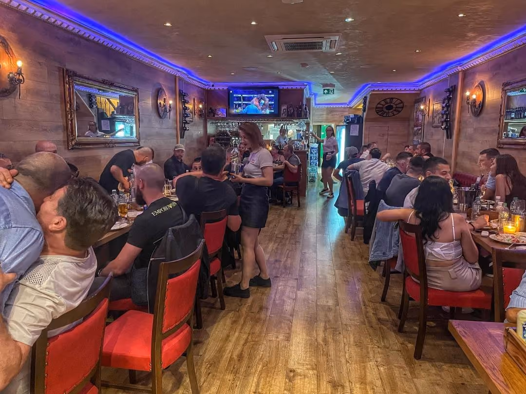Busy dining room at Rodina 2 with red chairs and blue lighting