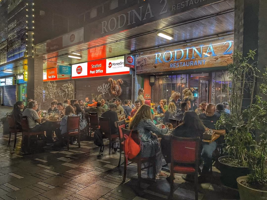 Guests dining at Rodina 2’s outdoor tables on Broadway in the evening